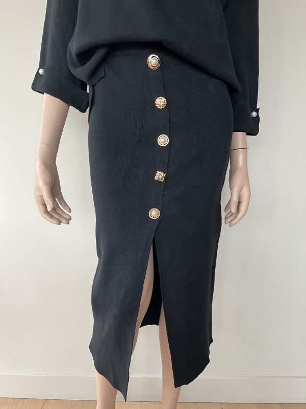 Rok in de kleur zwart met verschillende gouden knopen met parels.
