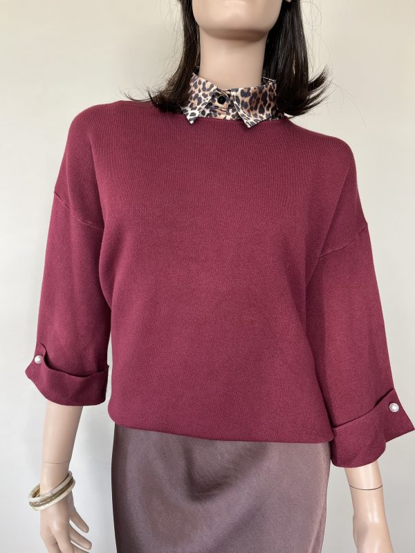 Trui in de kleur burgundy met ronde hals en driekwart mouwen. Als detail zit er een parel op de onderkant van de mouwen.