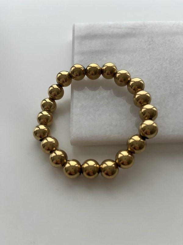 Elastische armband met goudkleurige kralen.