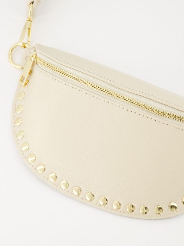 Hoogwaardig echt leren heuptas die ook als crossbody tas gedragen kan worden. De tas is afgewerkt met studs en goudkleurige hardware. Kleur: beige.